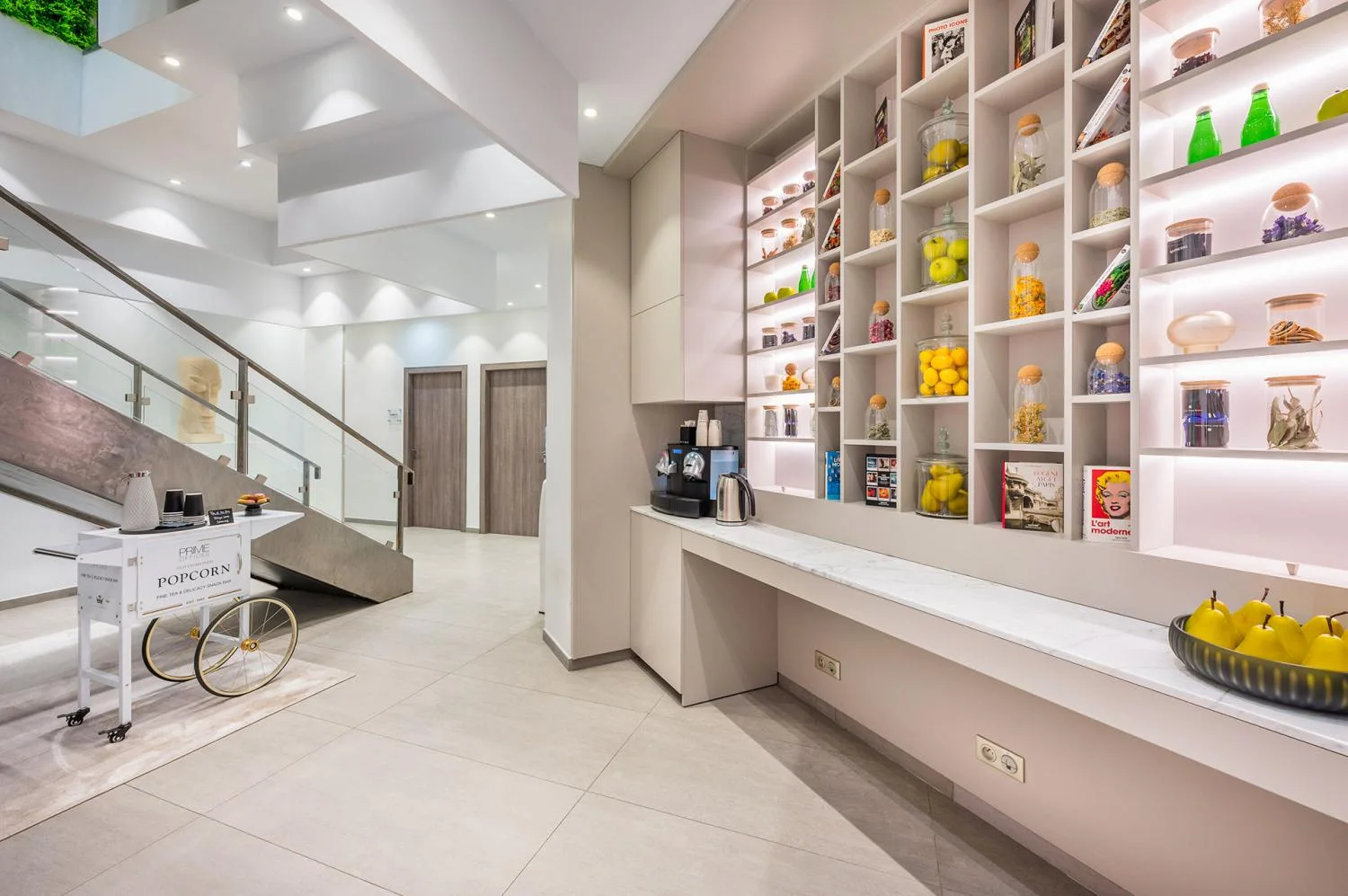 The coffee area with illuminated shelves and a staircase at Prime Offices Jardin Exotique